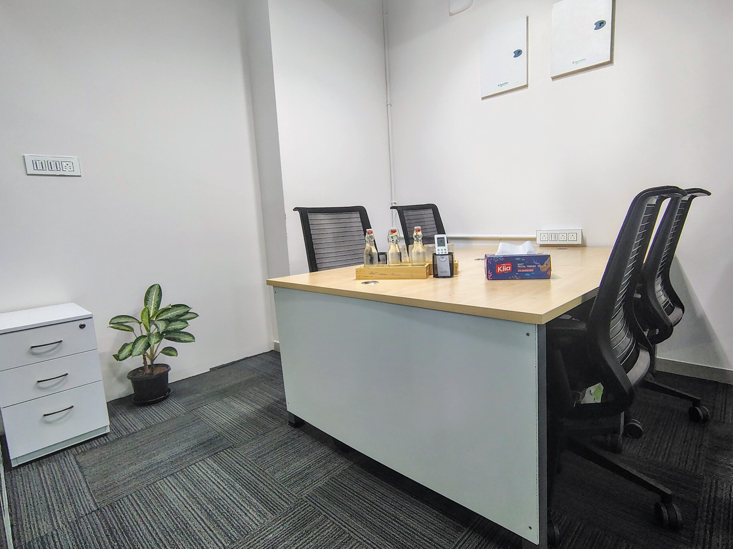 A cozy four-seater meeting room at Elite Co-Works, BTM Layout, Bangalore, featuring modern air conditioning, lush indoor plants, sleek office furniture, and essential amenities like power outlets, high-speed internet, and a serene ambiance — ideal for focused discussions in a premium coworking space.